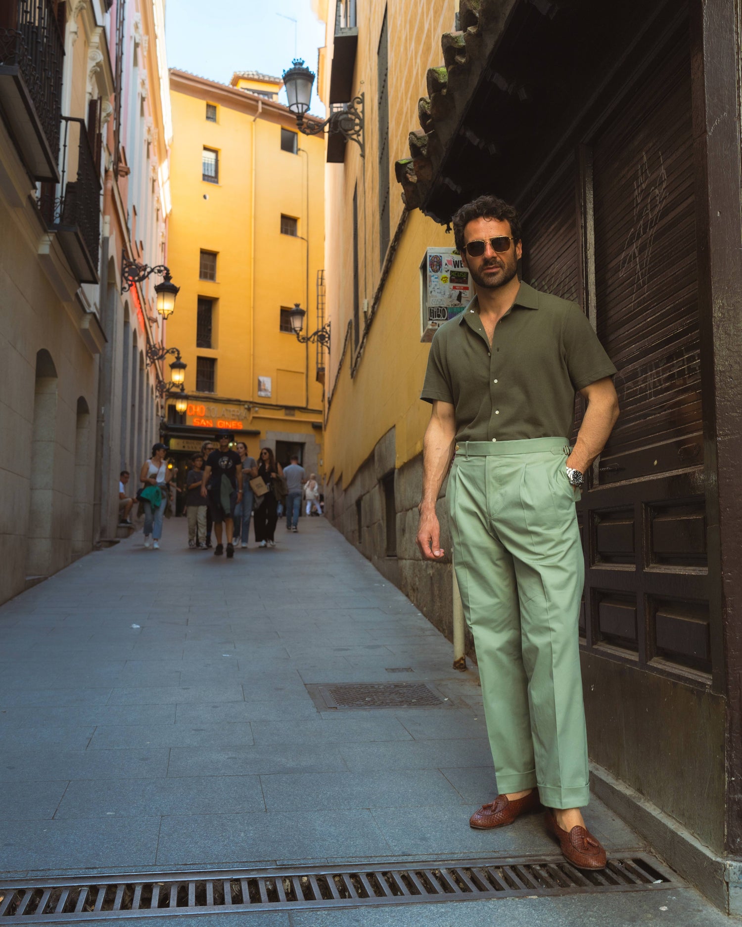 Model outside wearing the custom oxford polo shirt for men by Luxire in olive green hand in pocket