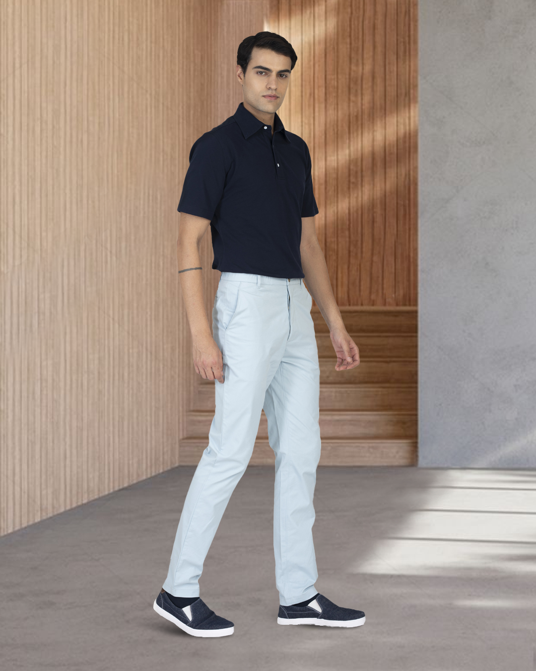 Model wearing the custom oxford polo shirt for men by Luxire in navy with white pants 2