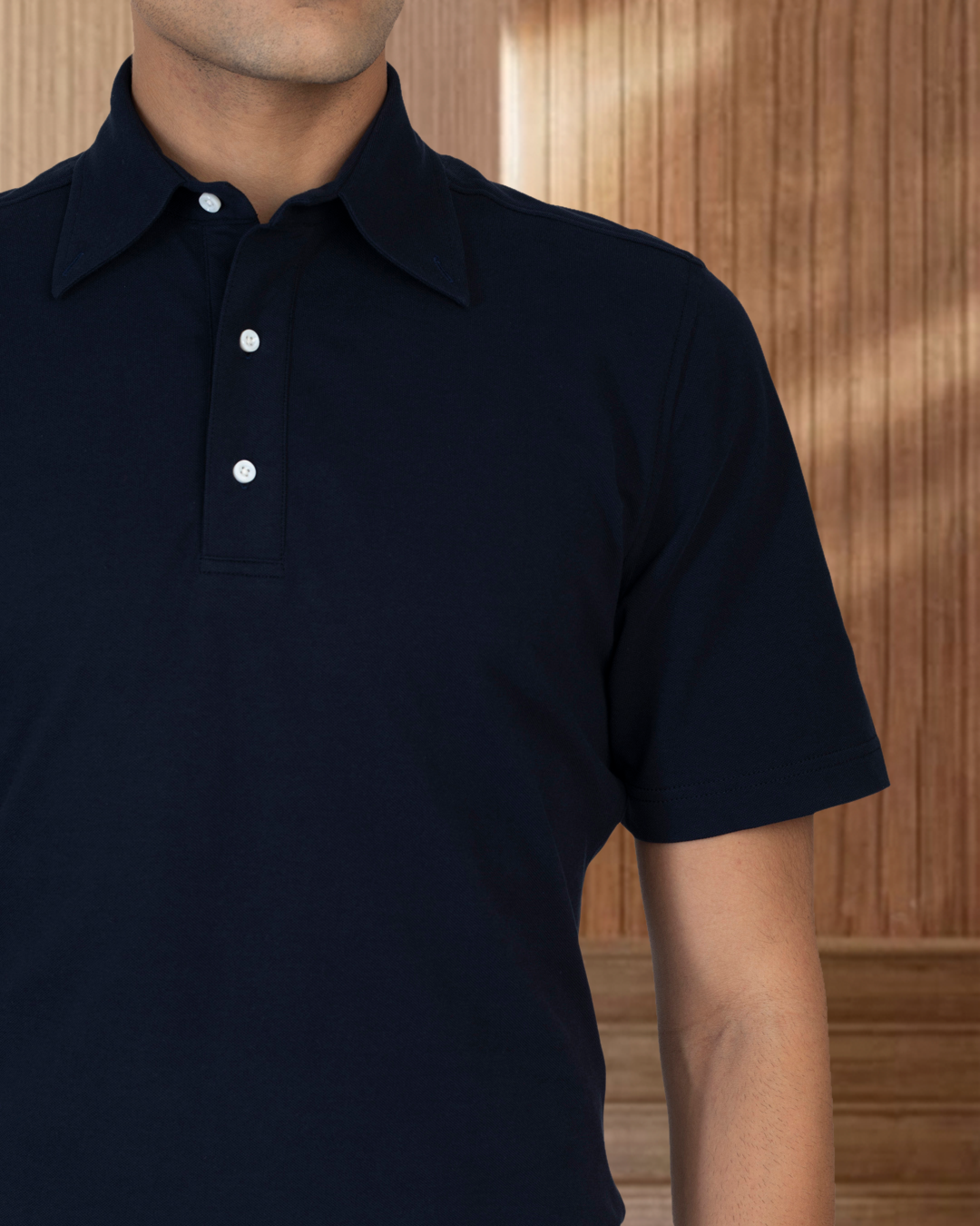 Close up of model wearing the custom oxford polo shirt for men by Luxire in navy