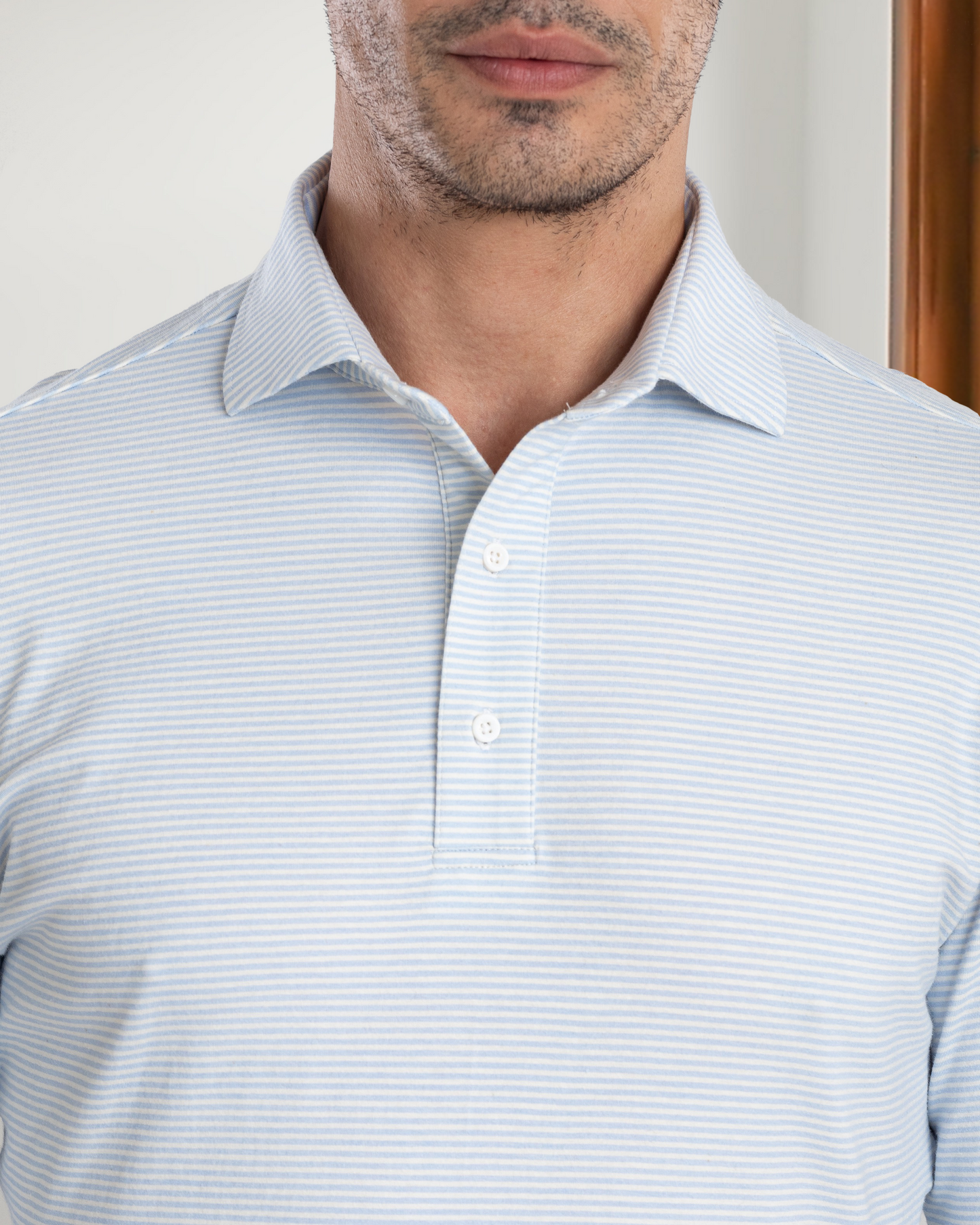 Model wearing the custom oxford polo shirt for men by Luxire in white and light blue candy stripes 2
