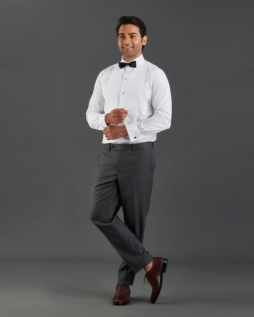 Model wearing mens tuxedo shirt by Luxire in white with black bow tie hands together